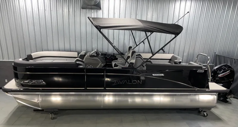 Slide: The Image of 2025 Avalon Catalina 2385 QL Tritoon boat with black canopy in a showroom. - 16