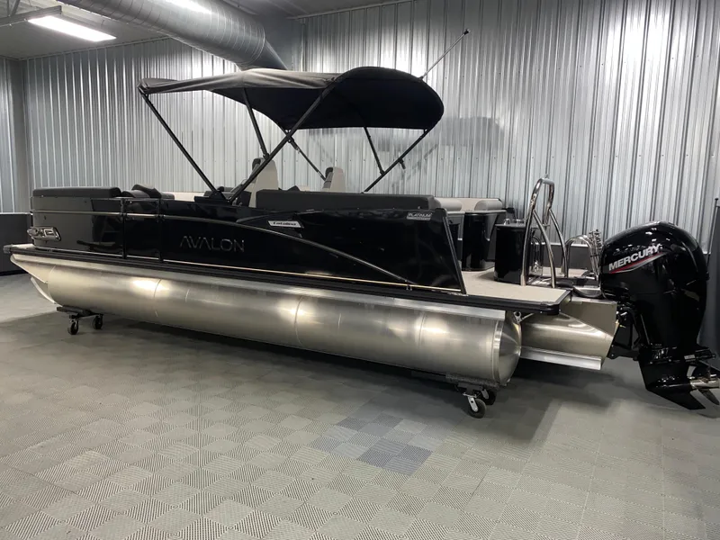 Slide: The Image of 2025 Avalon Catalina 2385 QL Tritoon boat with black canopy in a showroom. - 18