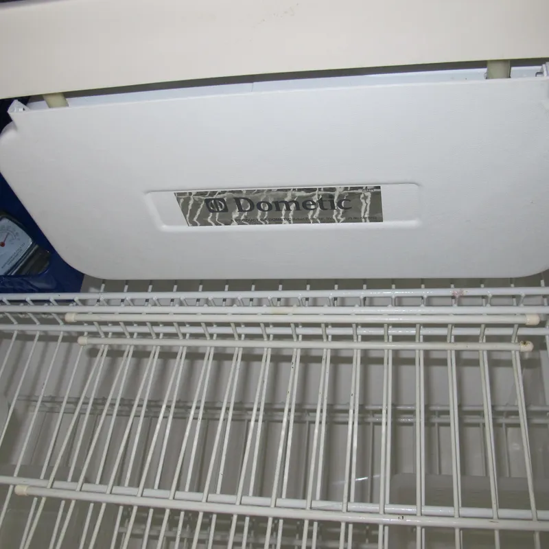 Slide: The Image of Dometic refrigerator inside a 1999 Catalina 42 MkII sailboat, showing wire shelves. - 31