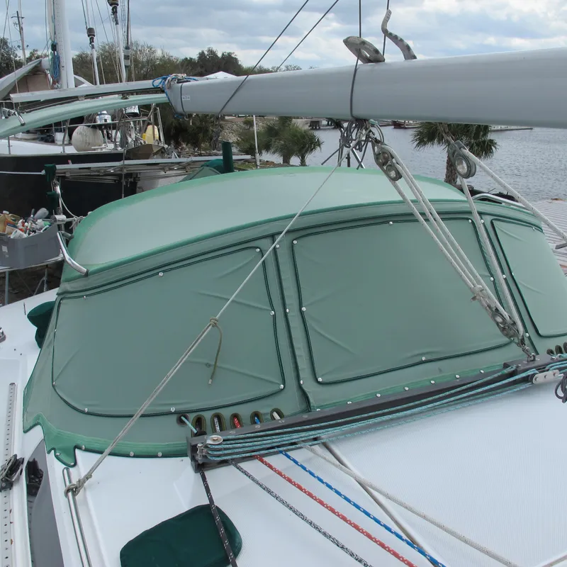 Slide: The Image of 1999 Catalina 42 MkII sailboat with green canvas cover, docked near water. - 4