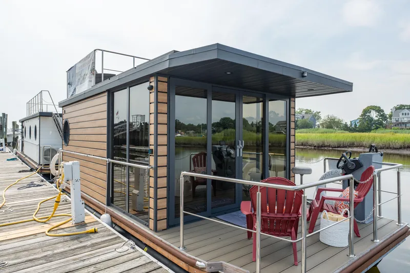 Slide: The Image of Modern 2024 Waterlodge Apart M houseboat docked, featuring glass doors and outdoor seating. - 1