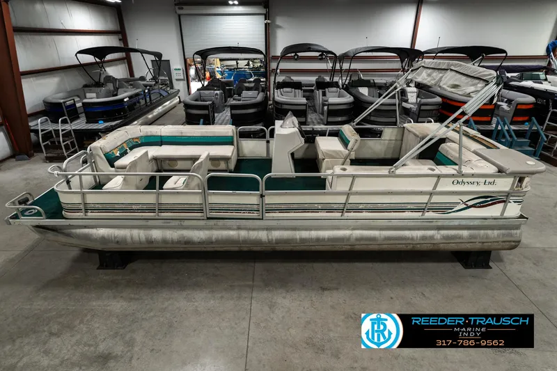 Slide: The Image of 1998 Odyssey 25 pontoon boat in showroom, surrounded by other boats. - 1