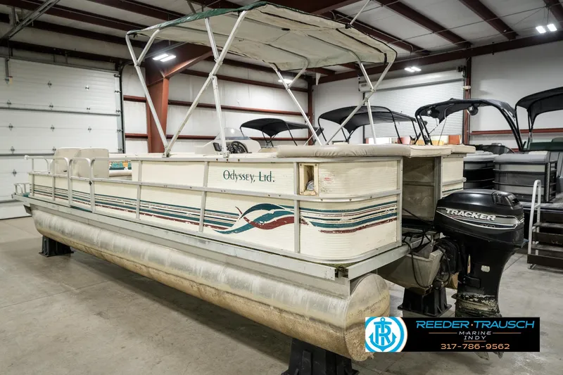 Slide: The Image of 1998 Odyssey 25 pontoon boat in a garage, featuring a canopy and outboard motor. - 10