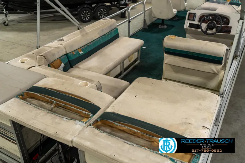 Slide: The Image of 1998 Odyssey 25 pontoon boat interior with worn seating and steering console. - 14
