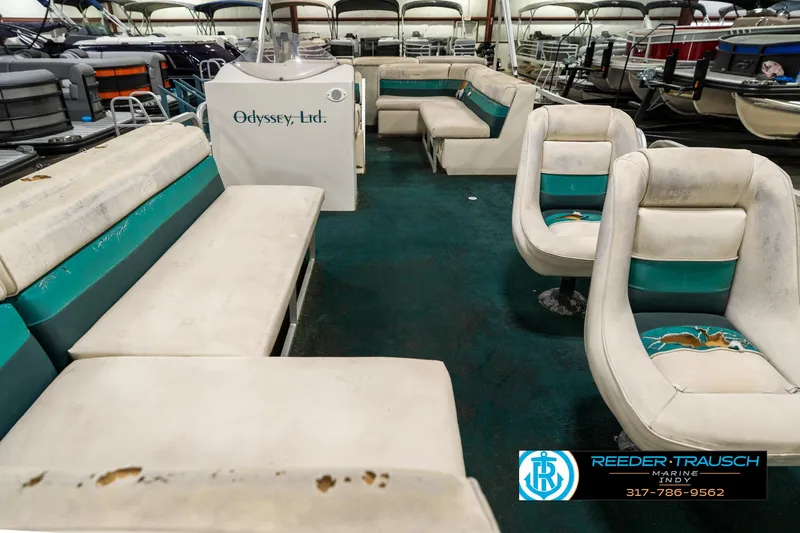 Slide: The Image of 1998 Odyssey 25 boat interior with worn seating and teal accents in a showroom. - 16