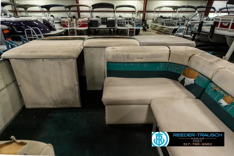 Slide: The Image of 1998 Odyssey 25 pontoon boat interior with worn seating in storage facility. - 18