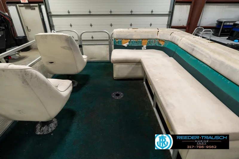Slide: The Image of Interior of a 1998 Odyssey 25 boat with worn seating and teal accents. - 21