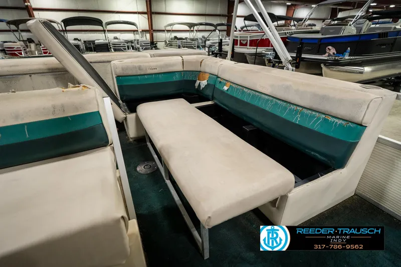 Slide: The Image of 1998 Odyssey 25 boat interior with beige and teal seating in a showroom. - 24