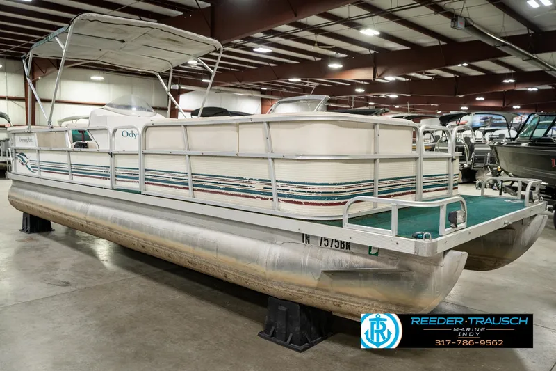 Slide: The Image of 1998 Odyssey 25 pontoon boat in showroom, featuring green carpet and canopy. - 5
