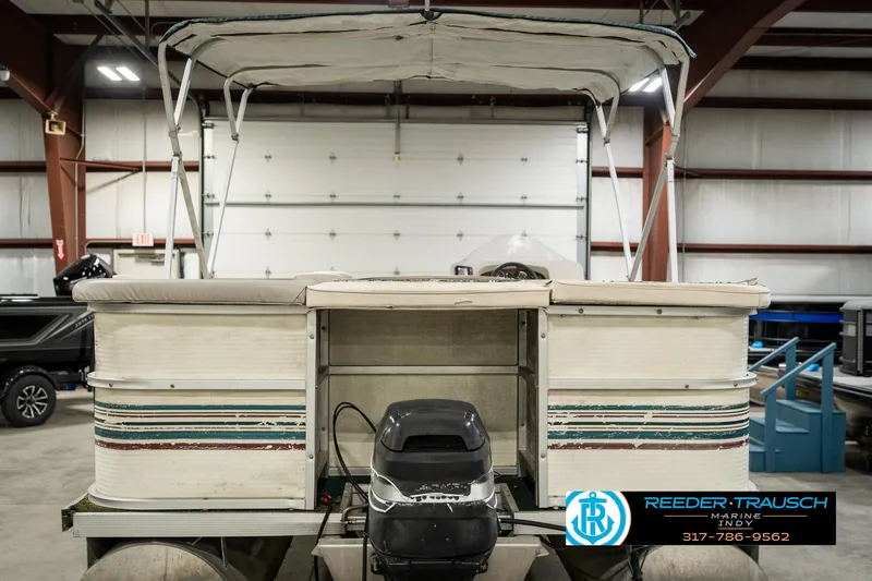 Slide: The Image of 1998 Odyssey 25 pontoon boat in a warehouse, featuring a canopy and motor. - 9