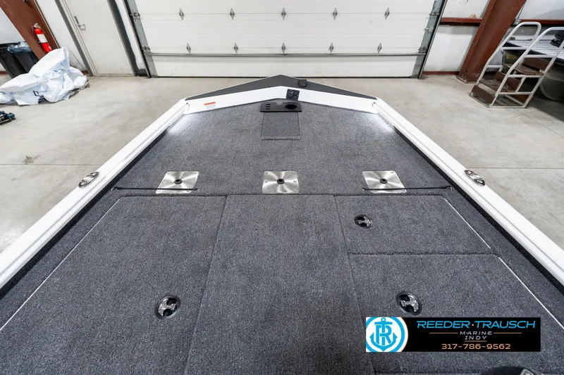 Slide: The Image of 2025 Lund 1775 Renegade boat interior with carpeted deck in a garage setting. - 16