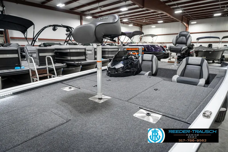 Slide: The Image of 2025 Lund 1775 Renegade boat interior in showroom, featuring seating and storage compartments. - 20