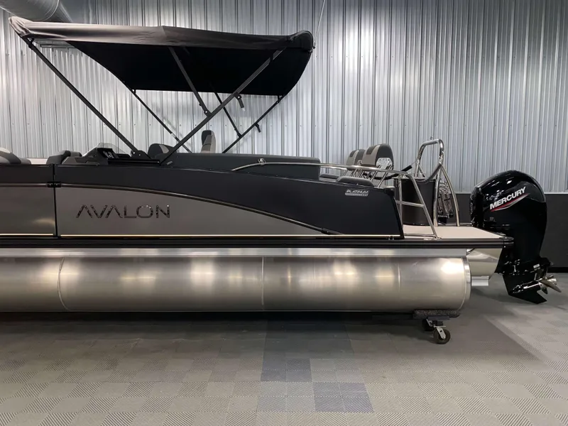Slide: The Image of 2025 Avalon Catalina 2385 QLS Tritoon with Mercury engine, displayed indoors. - 20