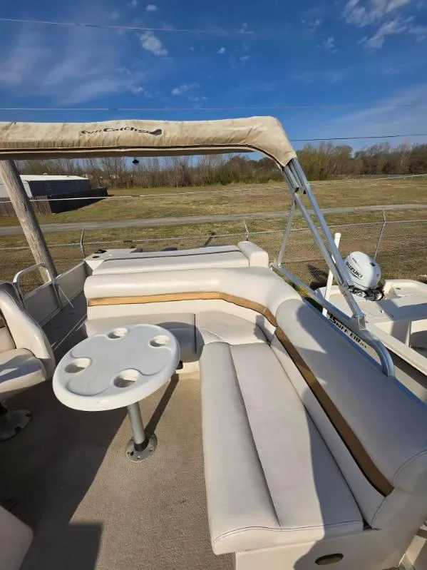 Slide: The Image of 2004 SunCatcher G3 22C pontoon boat with beige seating and table, under blue sky. - 17