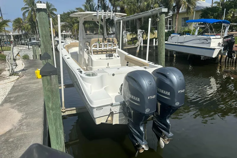 The Image of 2019 NauticStar 25XS boat with dual Yamaha 150 engines docked by the water. - 0