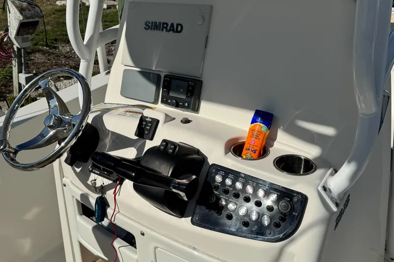 Slide: The Image of 2019 NauticStar 25XS boat console with steering wheel, Simrad display, and sunscreen bottle. - 12