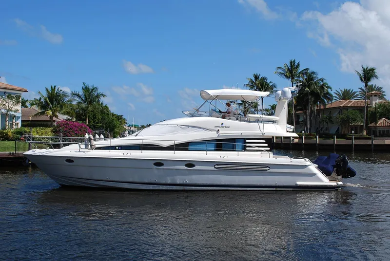 The Image of Fairline Squadron 2000 yacht cruising on a sunny day, surrounded by palm trees and waterfront homes. - 0