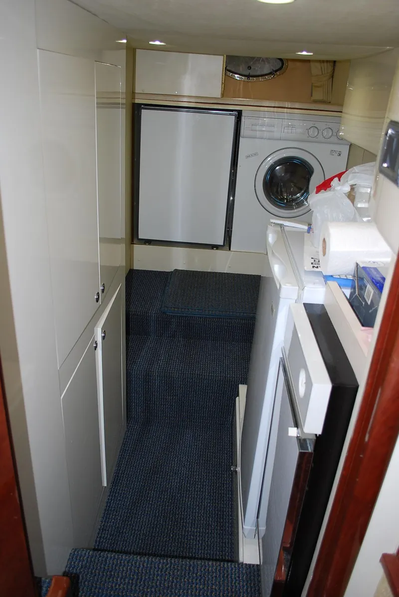 Slide: The Image of Laundry area inside a 2000 Fairline Squadron yacht, featuring a washing machine and storage cabinets. - 26
