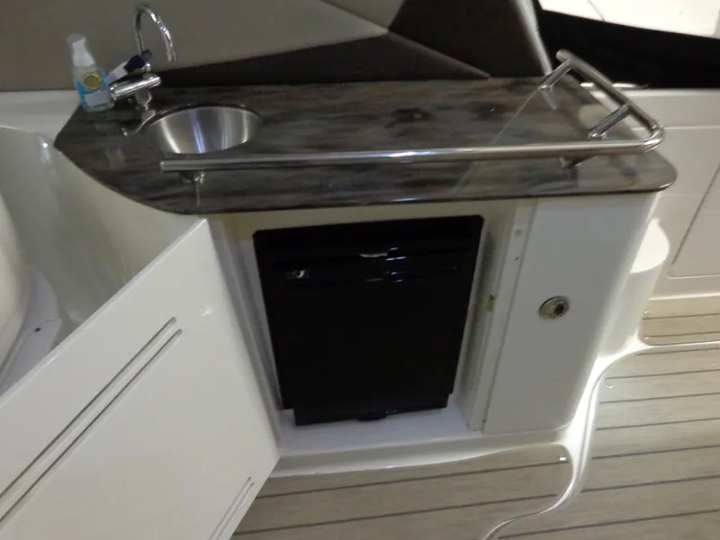 Slide: The Image of 2014 Sea Ray 370 Sundancer kitchenette with sink, countertop, and mini fridge. - 13