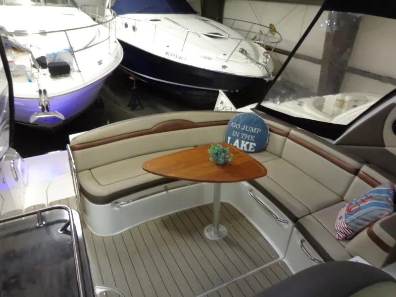 Slide: The Image of 2014 Sea Ray 370 Sundancer interior with seating and table in a boat showroom. - 14