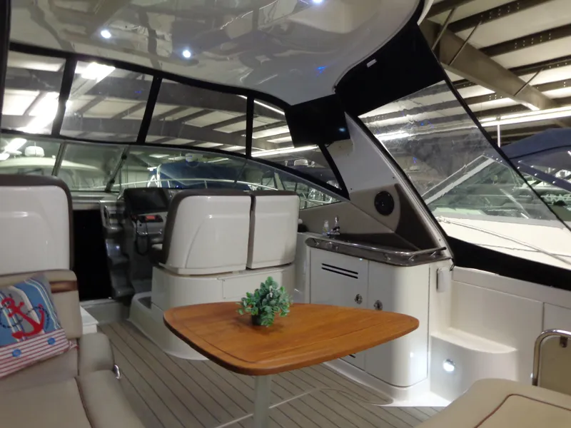 Slide: The Image of 2014 Sea Ray 370 Sundancer interior with seating, table, and helm in a well-lit cabin. - 17
