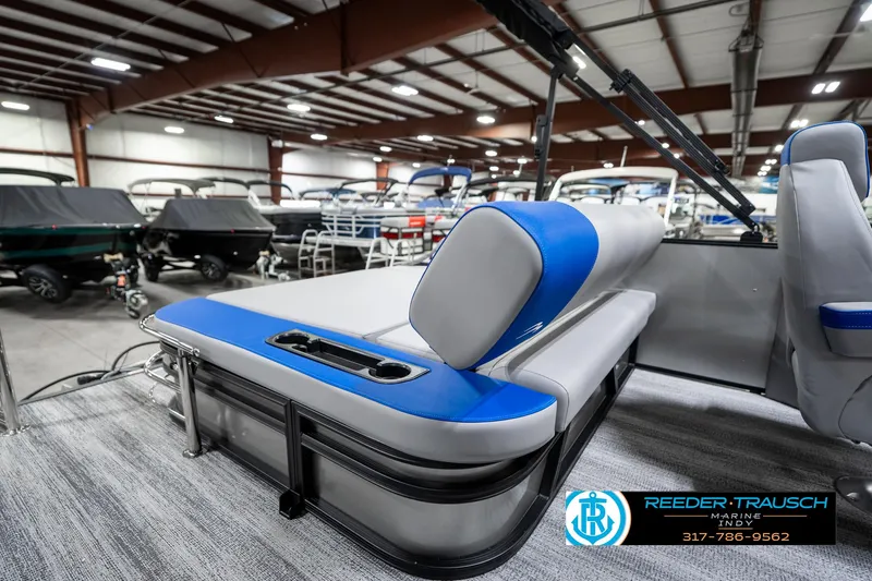 Slide: The Image of 2025 Bennington 20 SSB pontoon boat interior with blue and gray seating in showroom. - 24