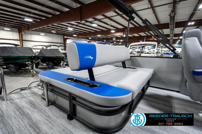 Slide: The Image of 2025 Bennington 20 SSB pontoon boat interior with blue and gray seating in showroom. - 26