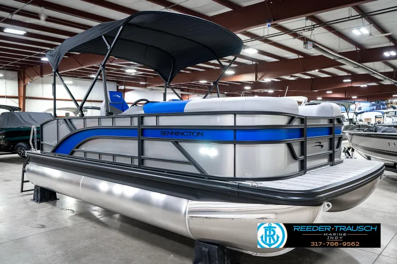 Slide: The Image of 2025 Bennington 20 SSB pontoon boat with blue accents in a showroom. - 6