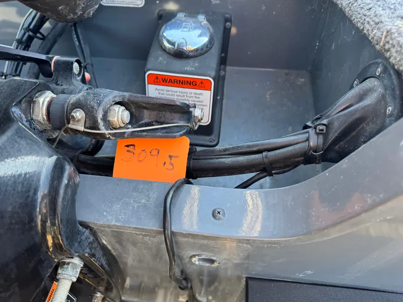 Slide: The Image of 2017 Tracker Targa V-18 Combo boat engine compartment with warning label and cables. - 17