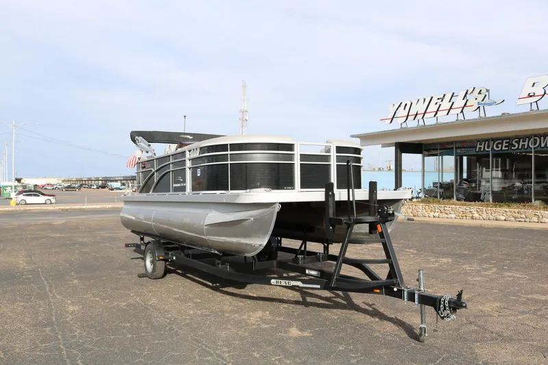 Slide: The Image of 2021 Bennington SX 20 Quad Bench pontoon boat on trailer in parking lot. - 1