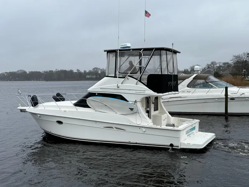 Slide: The Image of 2004 Silverton 34 Convertible boat on a calm lake with overcast skies. - 1
