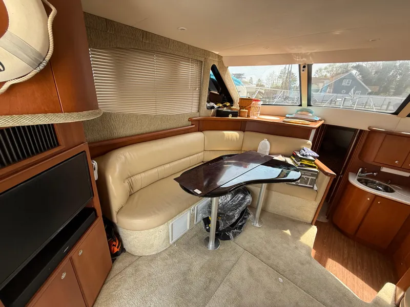 Slide: The Image of Interior of a 2004 Silverton 34 Convertible yacht with beige seating and a small kitchenette. - 12