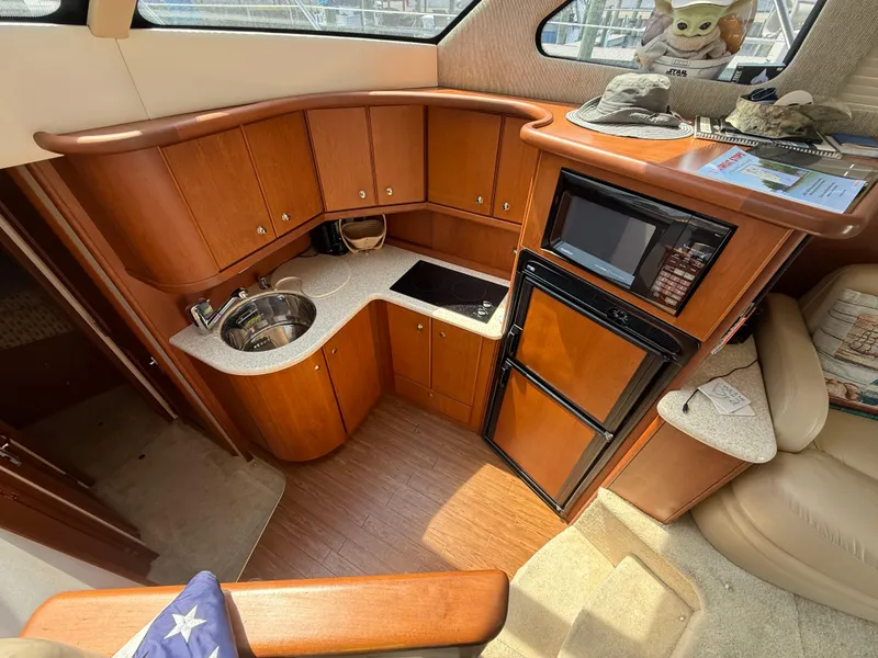 Slide: The Image of 2004 Silverton 34 Convertible yacht interior with kitchenette, featuring wood cabinetry and modern appliances. - 13