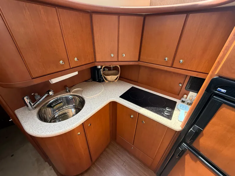 Slide: The Image of 2004 Silverton 34 Convertible yacht kitchen with wood cabinets, sink, and stovetop. - 14