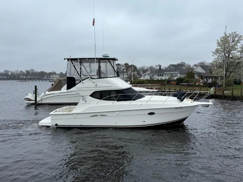 Slide: The Image of 2004 Silverton 34 Convertible yacht on a calm river near residential area. - 24