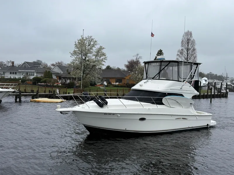 Slide: The Image of 2004 Silverton 34 Convertible boat on a calm river near residential area. - 3