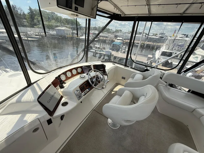 Slide: The Image of 2004 Silverton 34 Convertible yacht helm with white seating and marina view. - 4