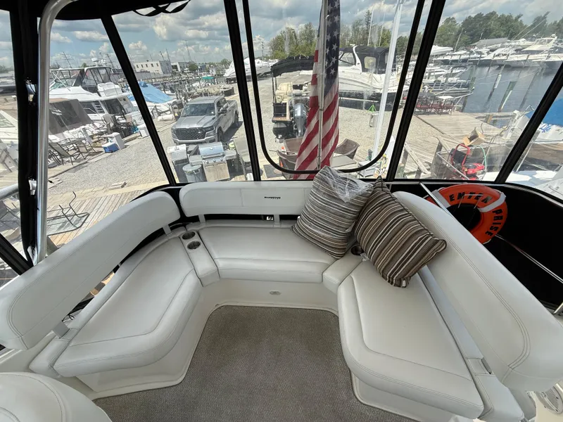 Slide: The Image of 2004 Silverton 34 Convertible yacht interior with white seating and striped cushions, dockside view. - 8
