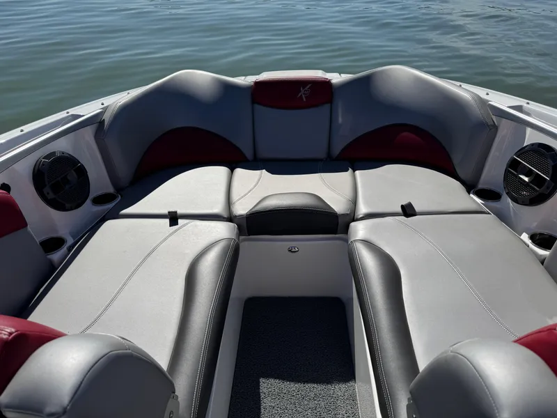 Slide: The Image of 2019 MasterCraft X46 boat interior with gray and red seating on calm water. - 12