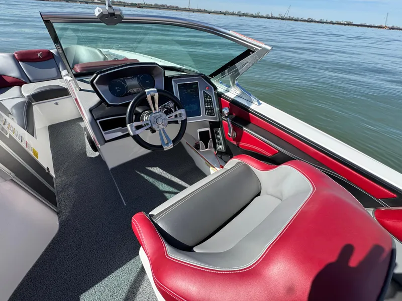 Slide: The Image of 2019 MasterCraft X46 boat interior with red and gray seating, steering wheel, and dashboard. - 17