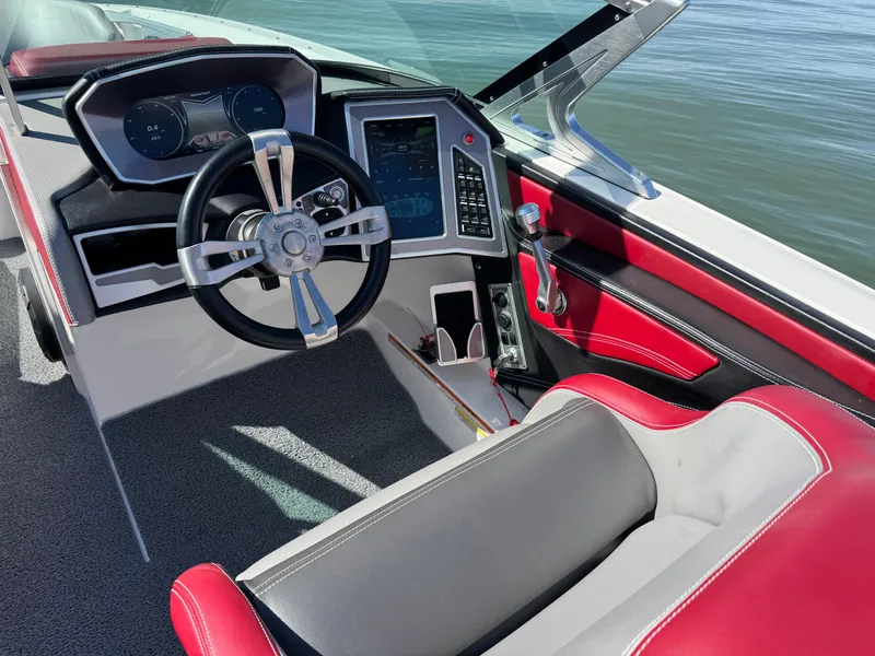 Slide: The Image of 2019 MasterCraft X46 boat interior with red and gray seating, modern dashboard, and steering wheel. - 18