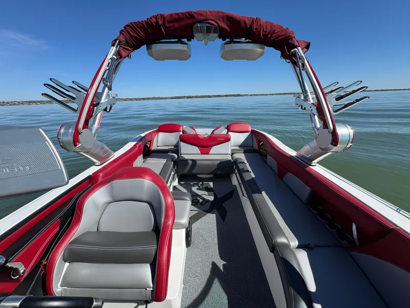 Slide: The Image of 2019 MasterCraft X46 boat interior with red and gray seating on a calm lake. - 24