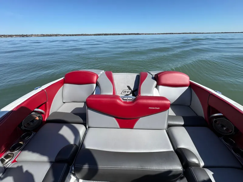 Slide: The Image of 2019 MasterCraft X46 boat interior with red and gray seating on a calm lake. - 27