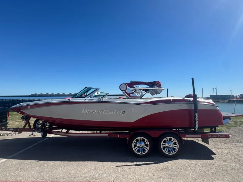 Slide: The Image of 2019 MasterCraft X46 boat on trailer, red and white, parked near waterfront. - 6