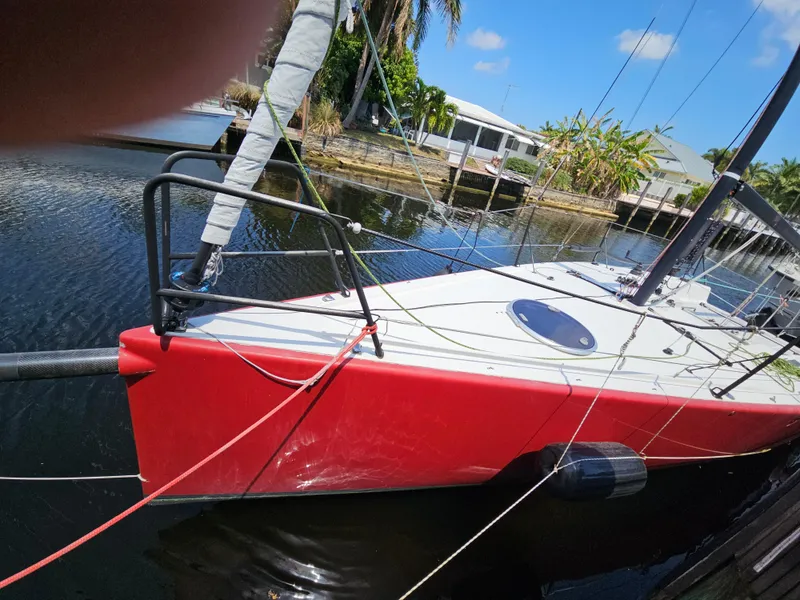 Slide: The Image of Red C&C Mega 30 One Design sailboat docked, 2014 model, in a serene canal setting. - 3