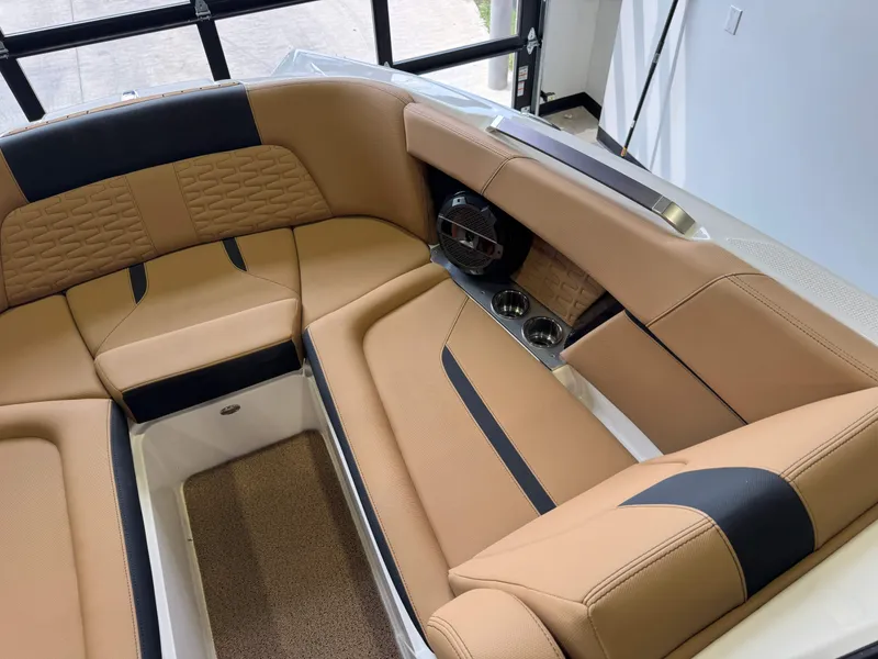 Slide: The Image of 2021 MasterCraft X24 boat interior with tan and black seating, cup holders, and speaker. - 20