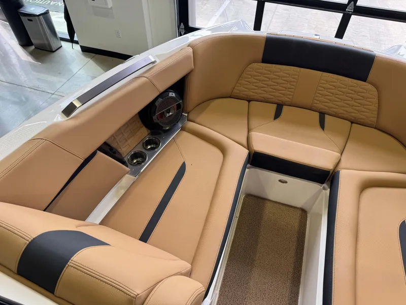 Slide: The Image of 2021 MasterCraft X24 boat interior with tan and black seating, cup holders, and speaker. - 21