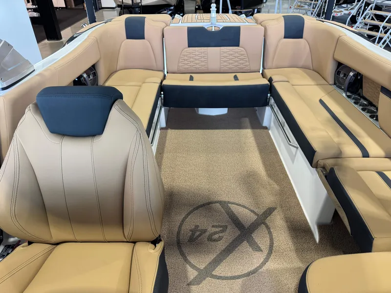 Slide: The Image of 2021 MasterCraft X24 boat interior with tan and black seating, spacious layout. - 24