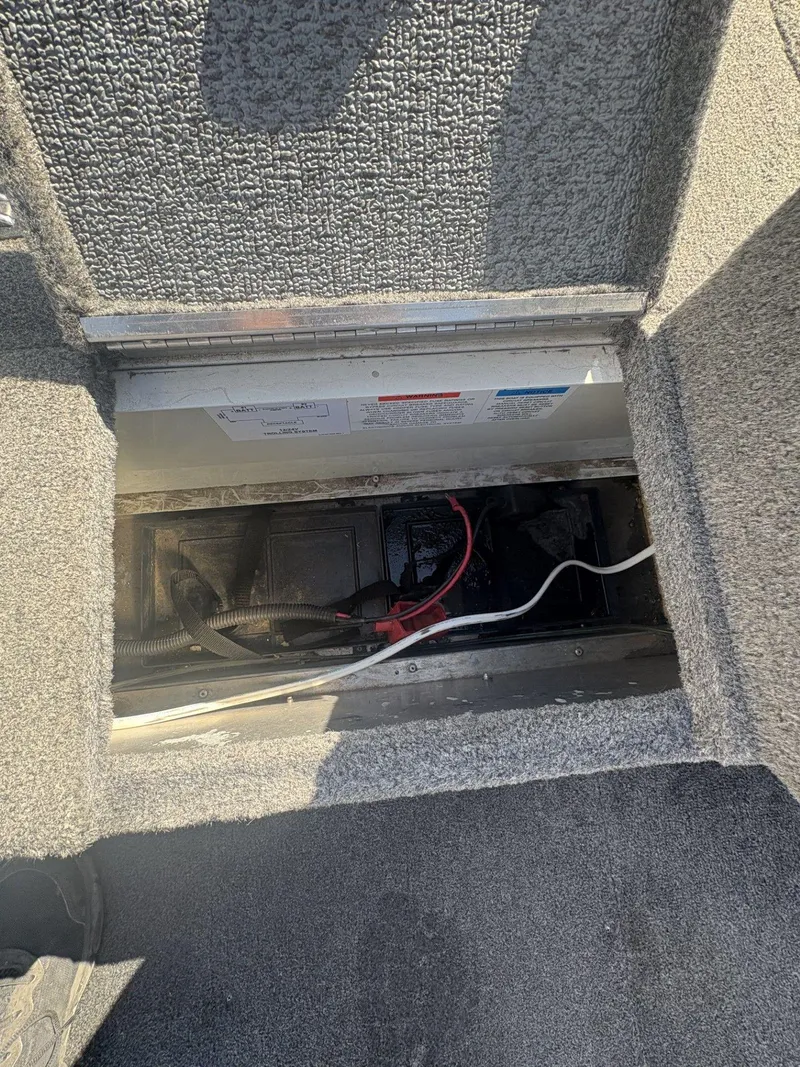 Slide: The Image of 2007 Alumacraft Navigator 165 CS battery compartment with wiring and carpeted interior. - 22