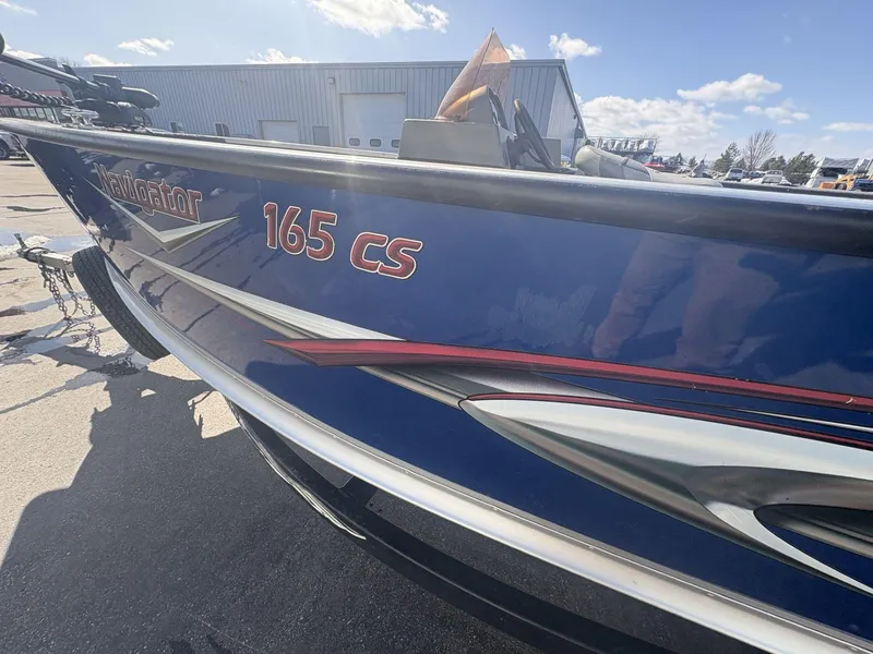 Slide: The Image of 2007 Alumacraft Navigator 165 CS boat with blue and red detailing, parked outdoors. - 9